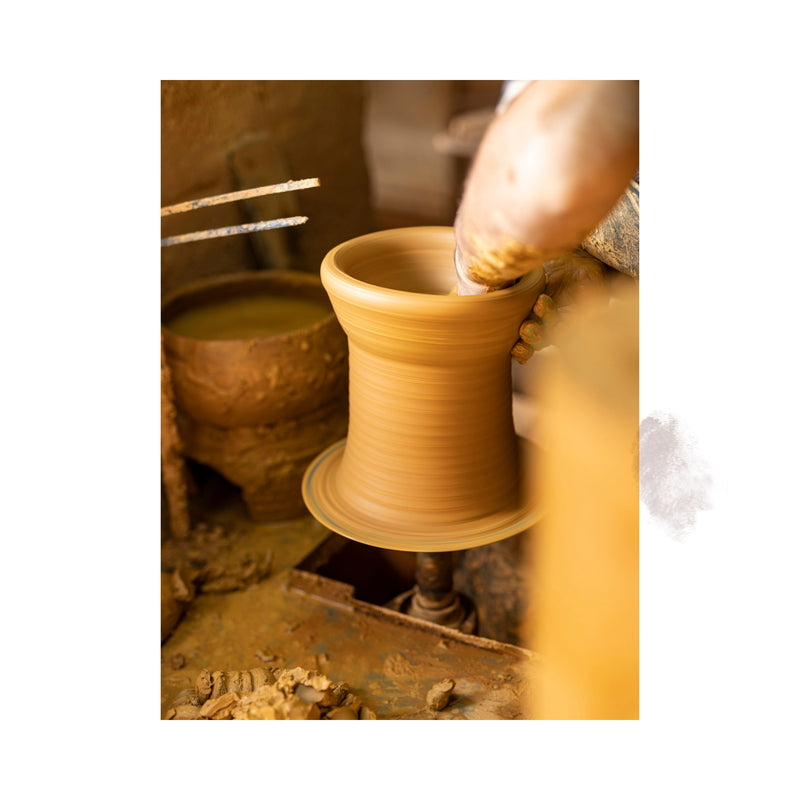 terracotta planter being shaped on pottery wheel