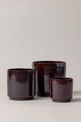 Set of three Terracotta glazed plant pots of different sizes in brown color