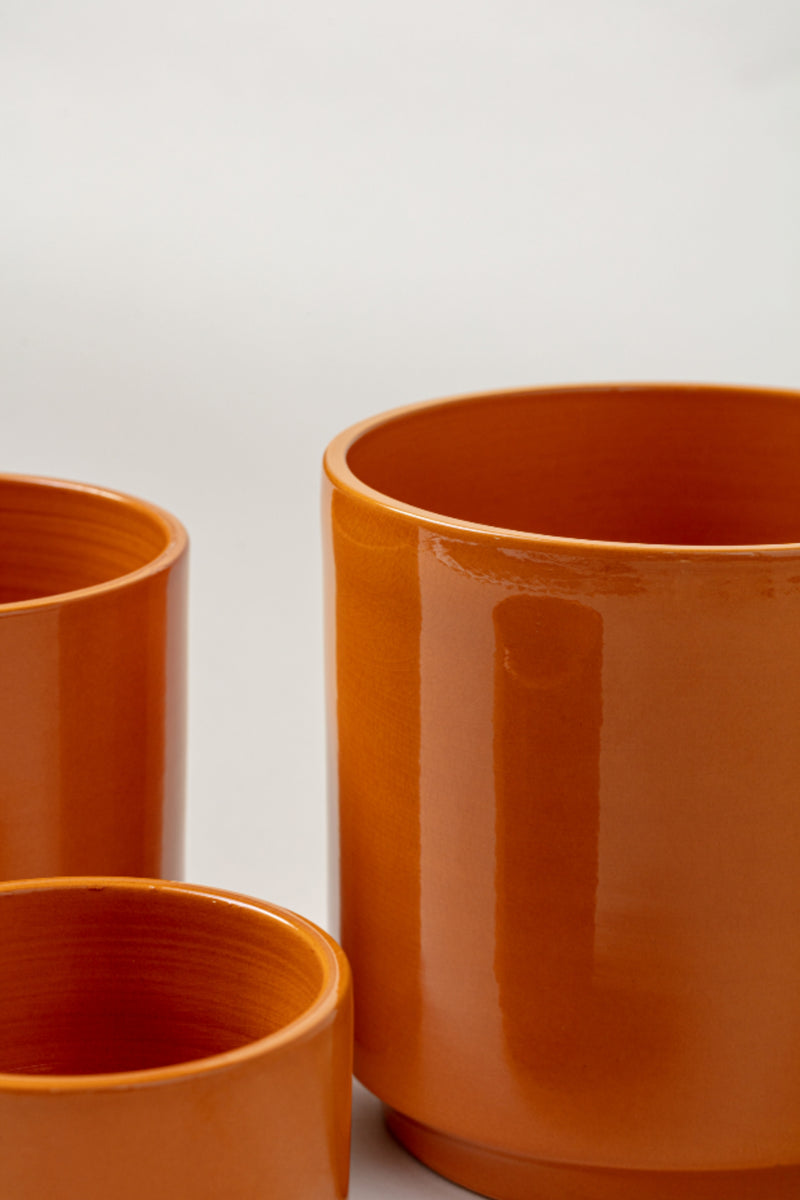 close up of set of three Terracotta glazed plant pots of different sizes in yellow color