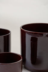 close up of set of three Terracotta glazed plant pots of different sizes in brown color