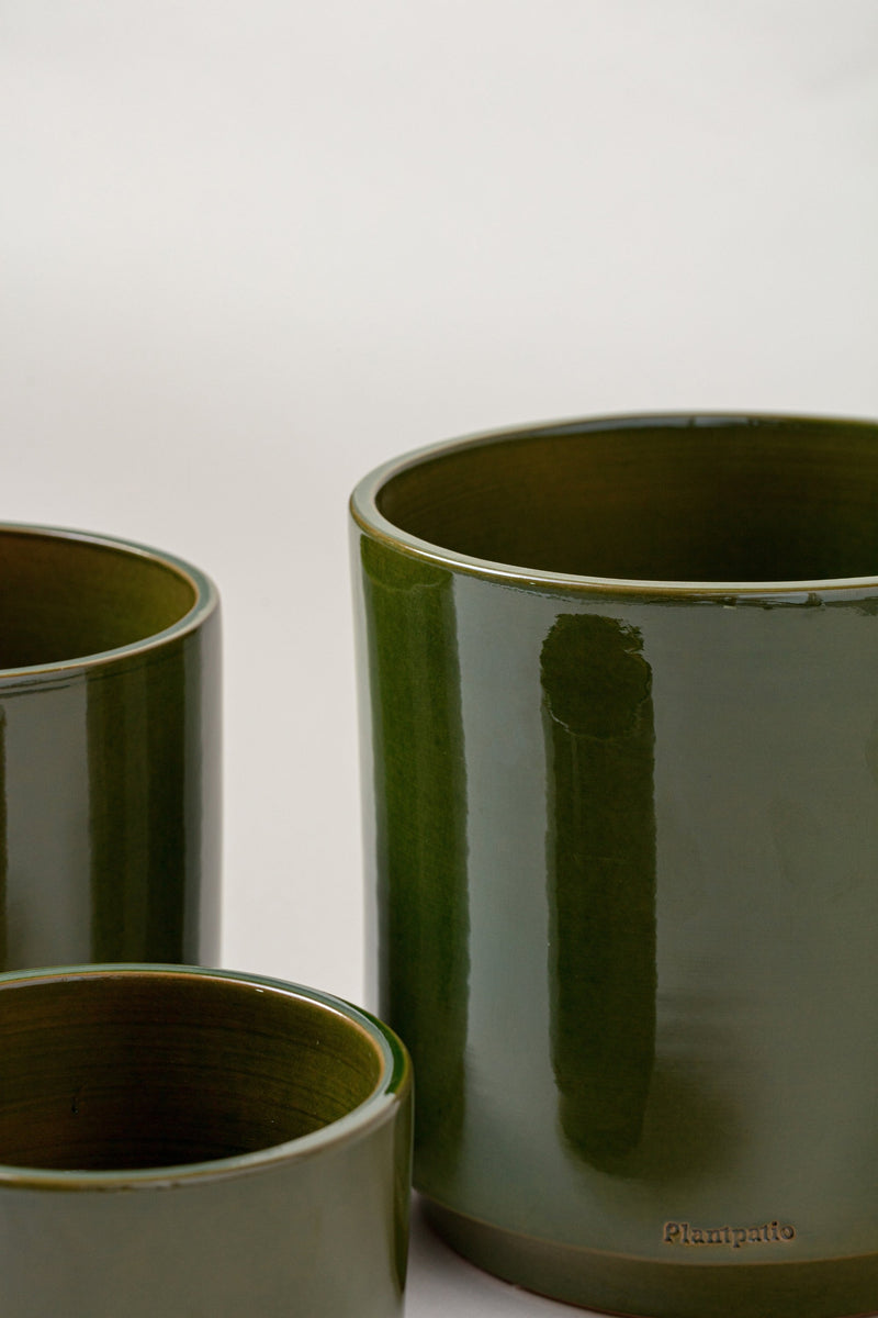 close up of set of three Terracotta glazed plant pots of different sizes in green color