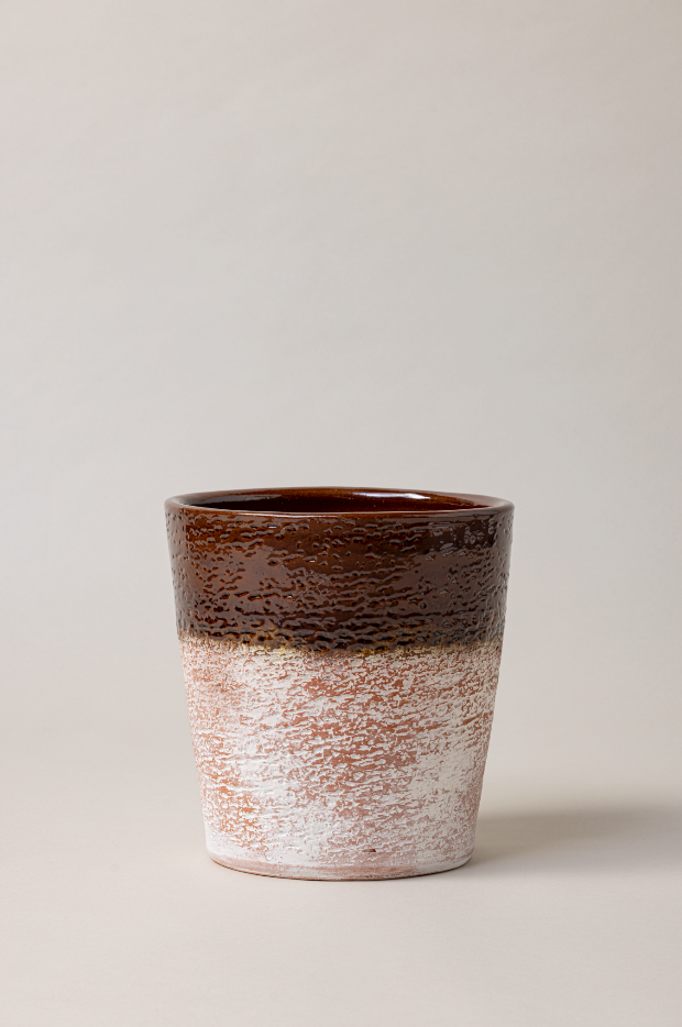Aged terracotta glazed plant pot in brown color.