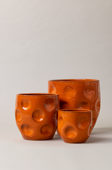 Set of 3 terracotta plant pots in orange color.
