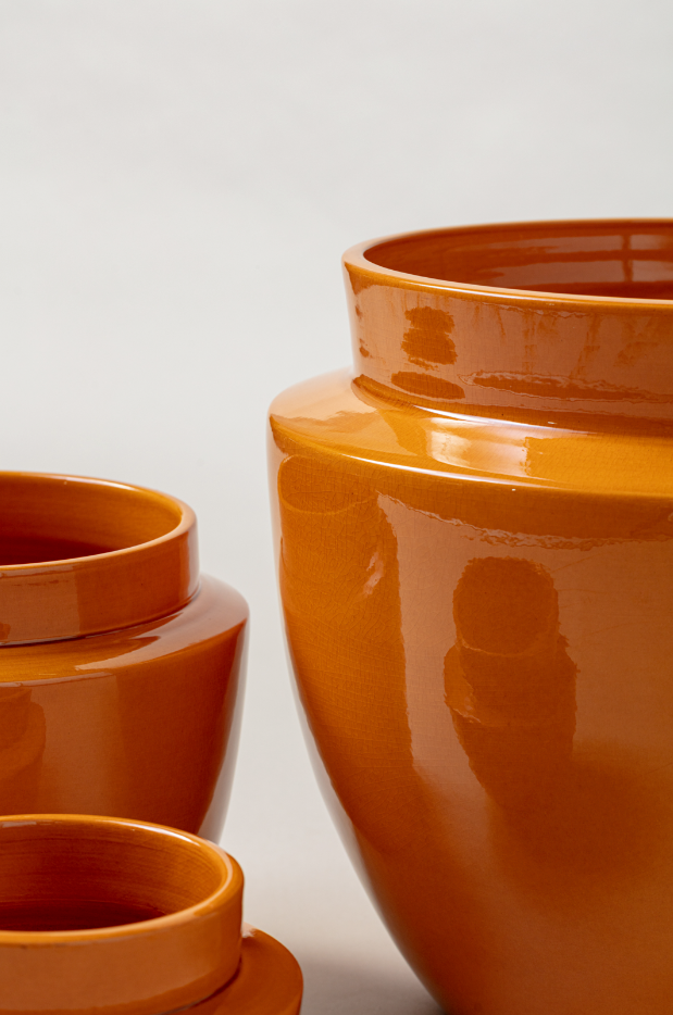 close up of set of three Terracotta glazed plant pots of different sizes in yellow color